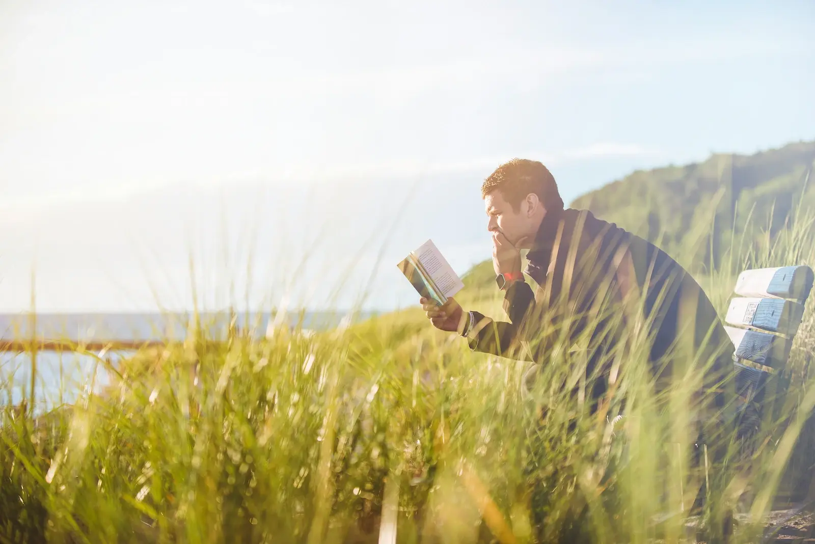 Hombre leyendo cerca del lago durante el día